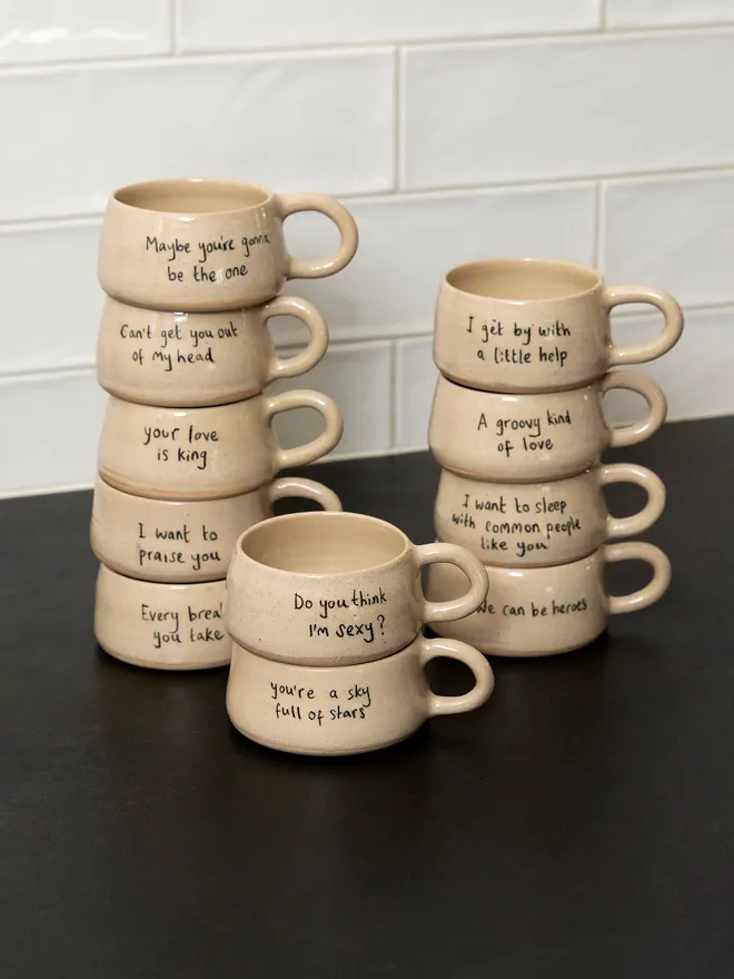 a full set of cream ceramic mugs with a range of phrases