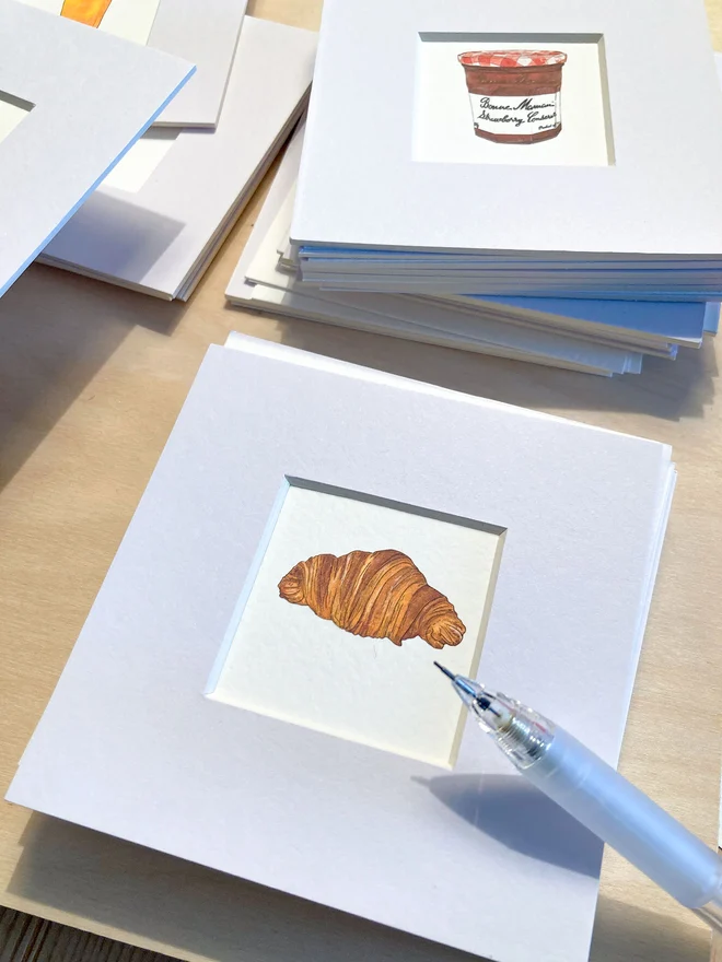 A tiny print with mount featuring a hand-drawn croissant Illustration