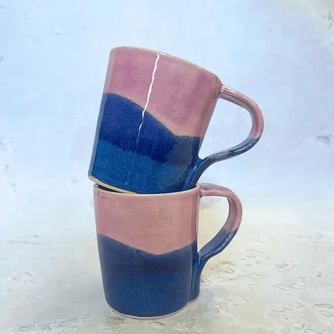 Landscape Standard Mug, a pair of colourful mugs stacked on top of each other on a stone surface. 