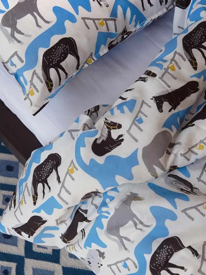 Horse Ranch Duvet Cover And Pillowcase, a blue horse themed set of a duvet cover and pillowcase in a bedroom. 