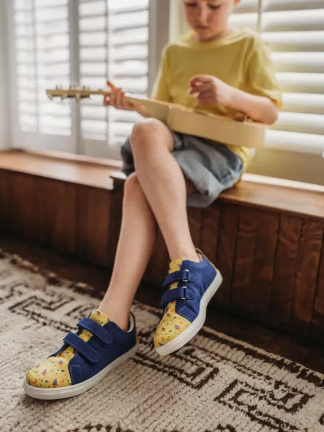 Little boy playing guitar wearing Pip and Henry blue and h=yellow space print sneaker