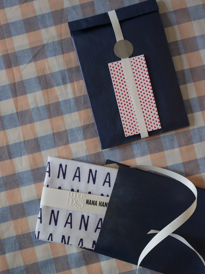 Optional gift wrap for NANA hankie, navy paper and patterned gift card on a gingham tablecloth