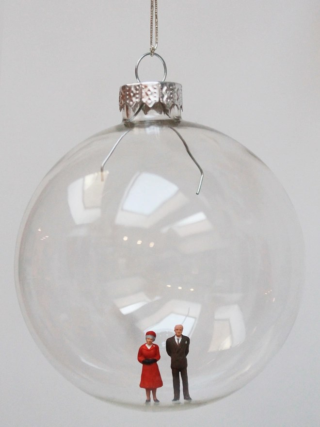 Miniature figure of a Queen Elizabeth II and Prince Phillip in a glass hanging christmas bauble 