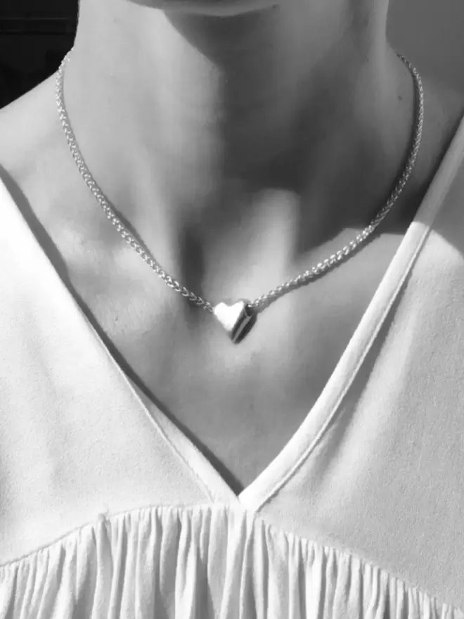 a model wearing a short chunky love heart pendant
