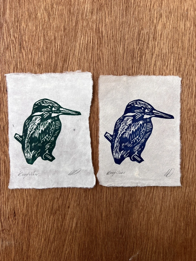 Hand-printed green and blue kingfisher variations lino print on natural handmade paper, featuring a bold graphic illustration of a kingfisher.