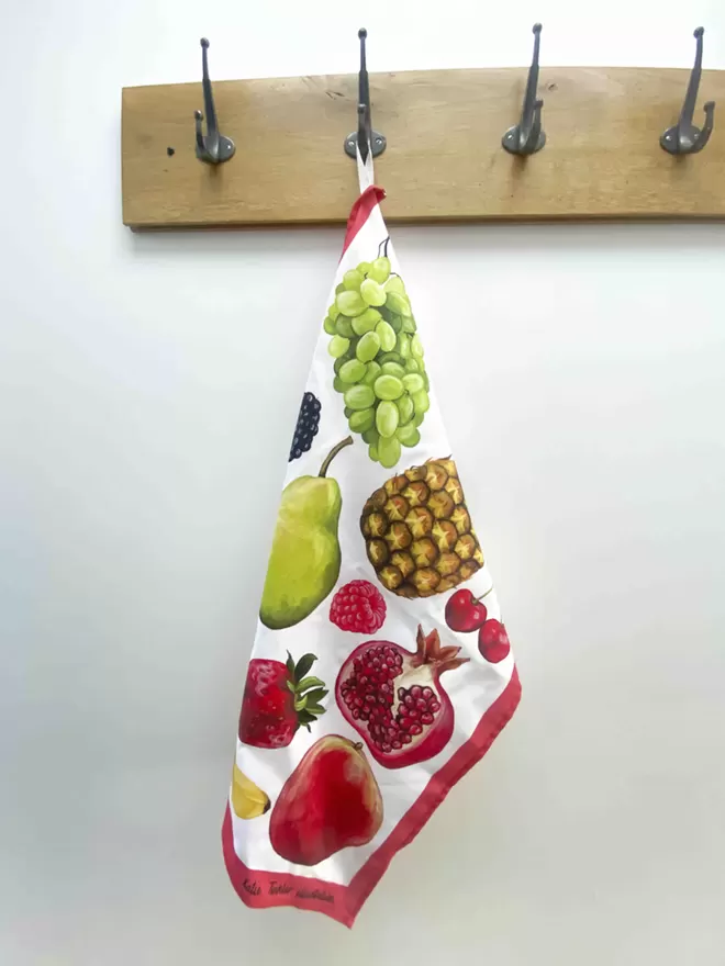 A fruit themed tea towel hanging on a coat hook
