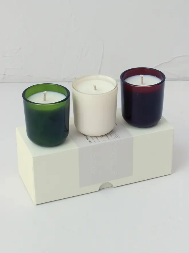small aromatherapy soy candles (set of 3). candles arranged in row on top of box packaging.