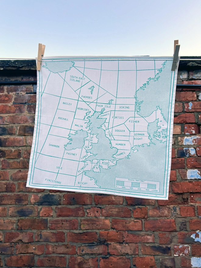 A Mr.PS Shipping Handkerchief in green hangs on a washing line outside