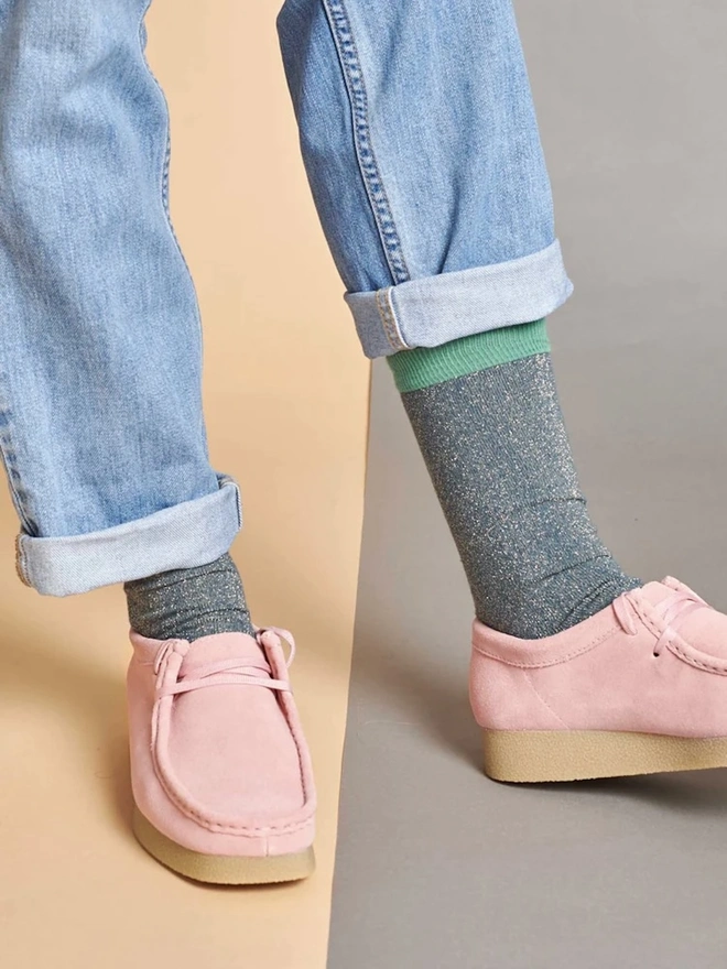 Women's Glitter Organic Cotten Ankle Socks, a woman wearing a pair of colourful patterned socks above a decorated surface. 