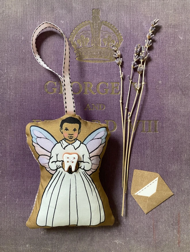 Black boy tooth fairy doll holding a ceramic white tooth with a ribbon for hanging