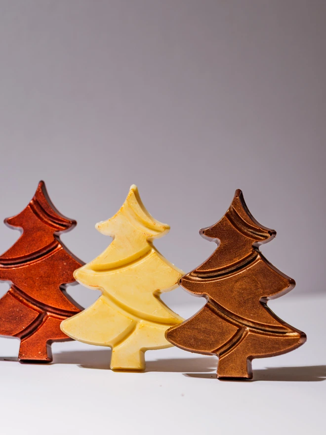 3 solid chocolate Christmas Trees, one each in Milk, White and Dark chocolate, decorated with bronze, copper and gold cocoa butter dust. 