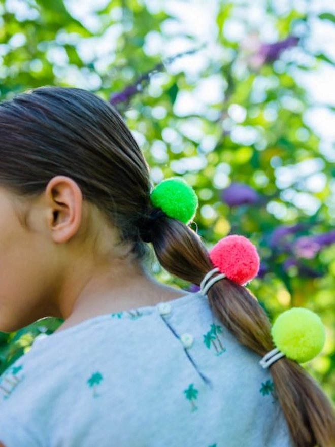 pom pom hair bobble elastics in young girl's hair