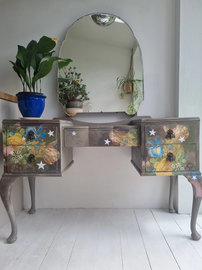 Vintage painted dressing table and chair. Painted in coffee grey and decorated using layered antique florals with yellow and blue accents and finished with hand-cut white paper stars. Text reads in blue 'think happy thoughts'. Heavily distressed finish.