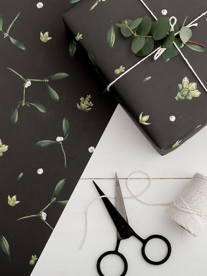 Black based wrapping paper with mistletoe illustration elements