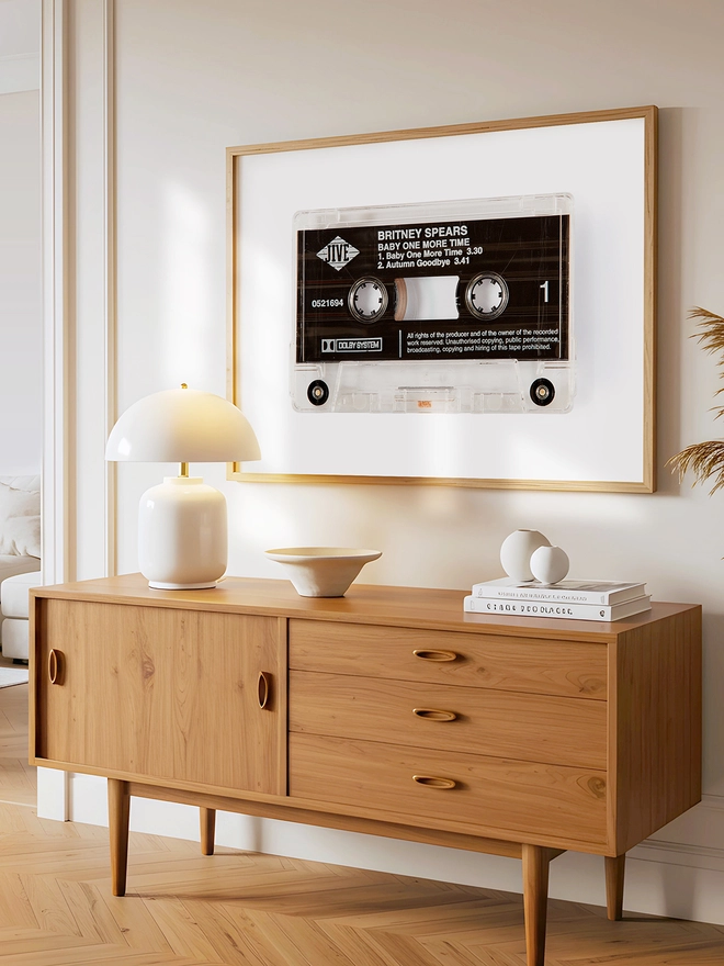 baby one more time britney spears cassette print. framed print hung above wooden dresser.