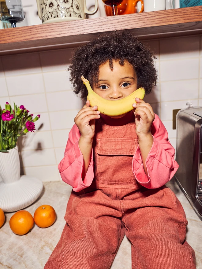 Child wearing turquoise overdyed Kai dungarees showing unique color variations and comfortable fit