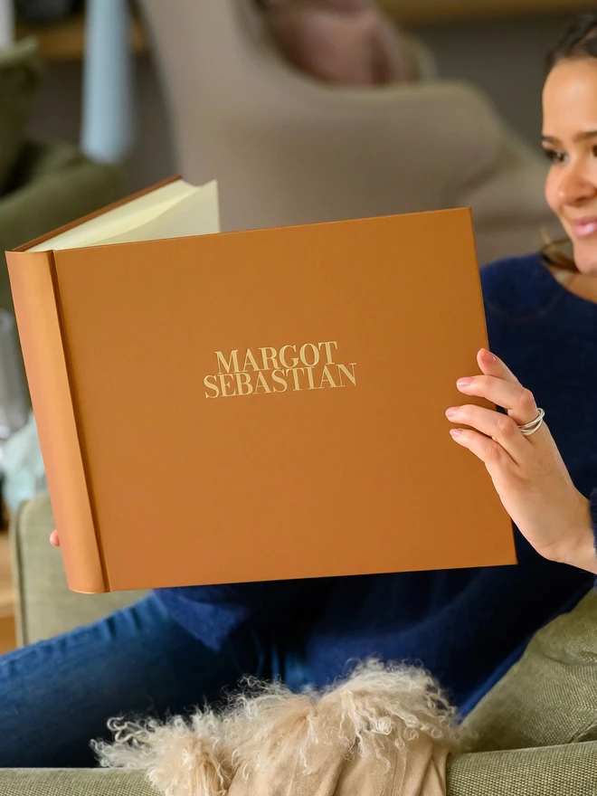 A woman looking at a Personalised Large Wedding Guest Book With Two Names,  in Butterscotch colour.