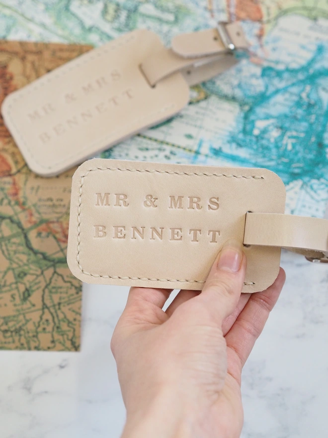 Personalised leather luggage tag. Handmade natural cream leather luggage tags, personalised with Mr & Mrs surname. Amongst colourful maps, ready for travelling.