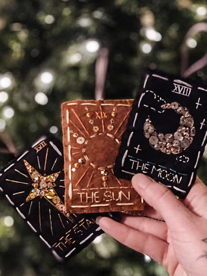 A handcrafted felt ornament with sequins and embroidery depicting "The Sun" tarot card. Also accompanied by “The Star and The Moon”