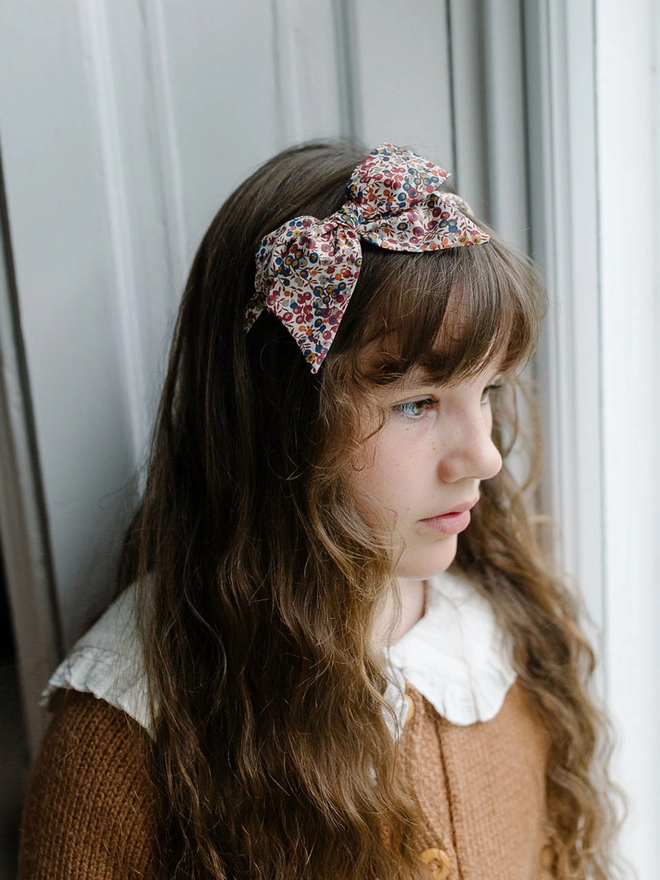 Girl with long brown hair and liberty alice band