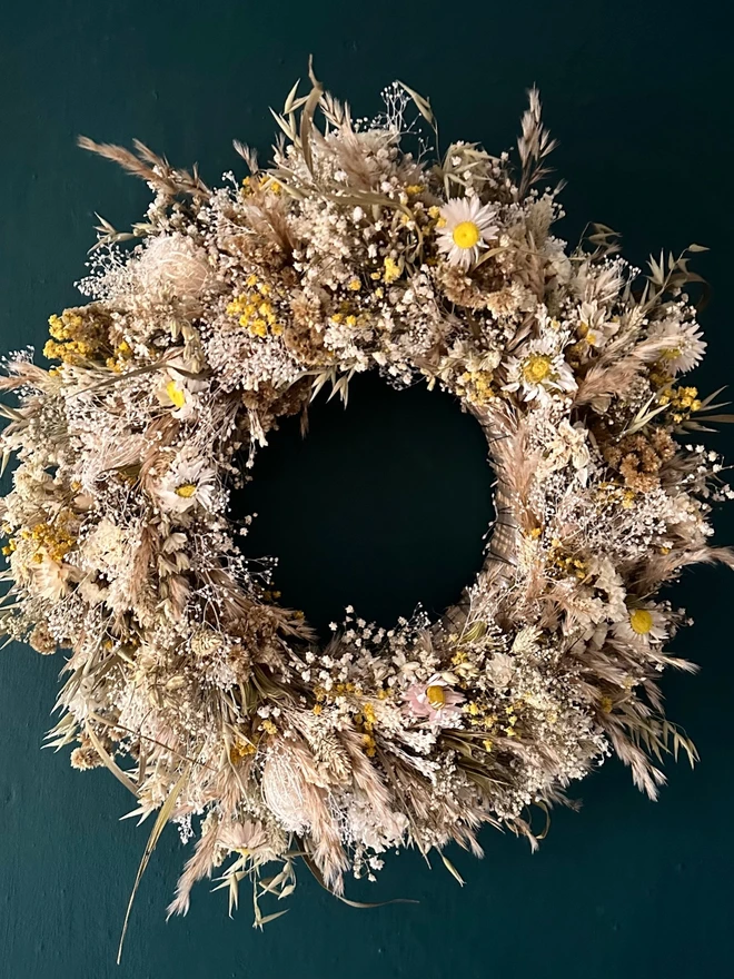 dried floral dried flower door wreath. a dried flower wreath made of various dried flowers and foliage hung on a forest green wall.