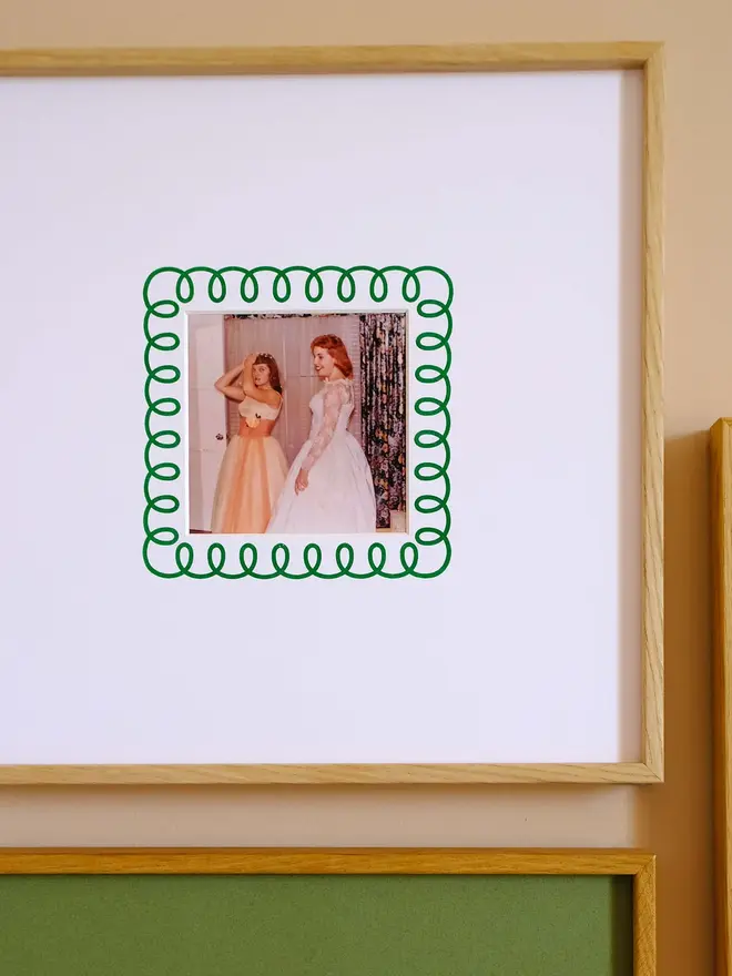 The frill instax square mount frame with a mount featuring a decorative frill border around a centered Instax Square photo, displayed on a neutral beige wall.