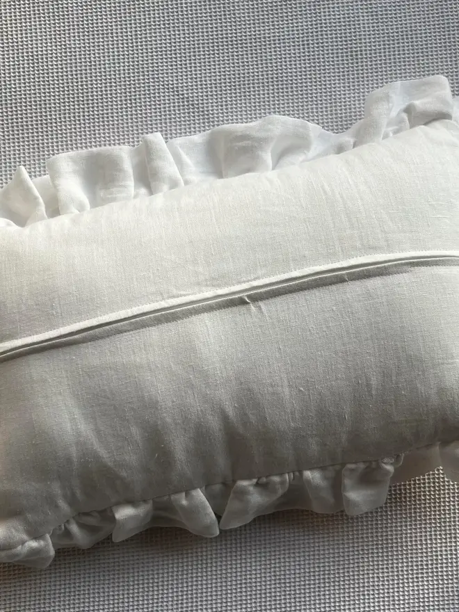 Personalised Handmade Embroidered Linen Cushion With Ruffle, back seam of the cream cushion. 