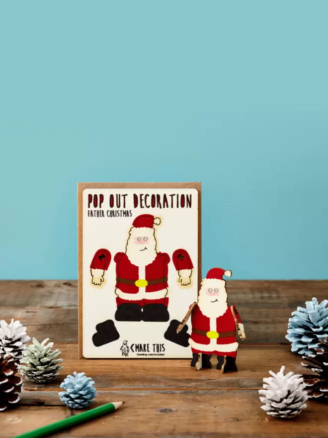 Pop out Father Christmas decoration and Merry Christmas card and brown kraft envelope displayed on a wooden desk