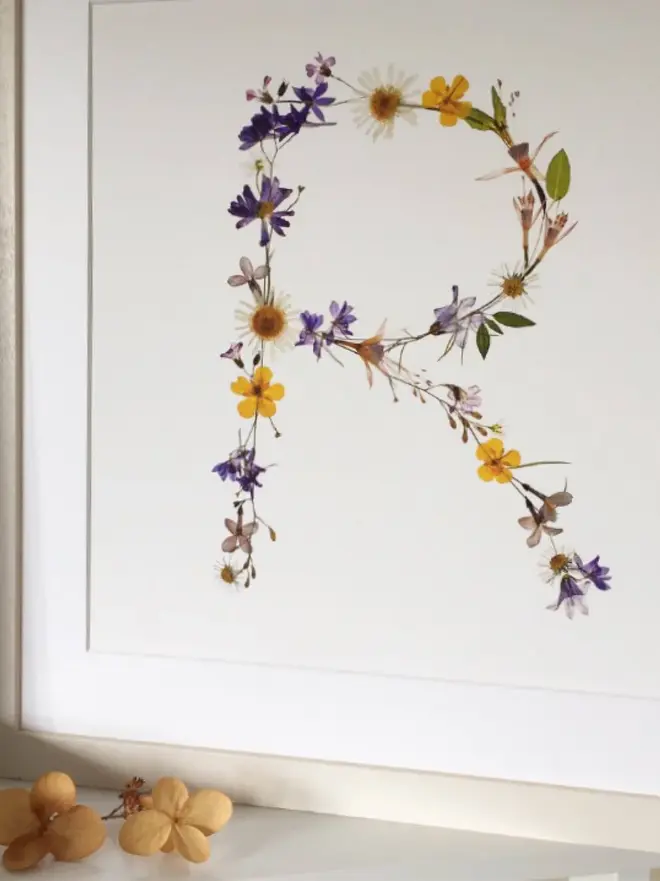 Pressed Wildflower Letter Print, a wildflower alphabet letter print sitting framed. 