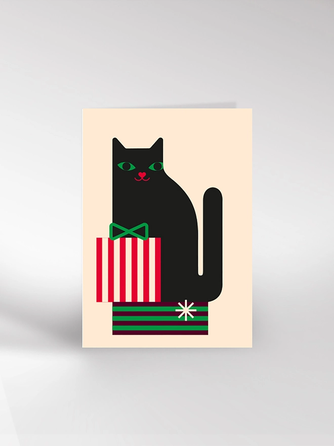 Contemporary illustrated Christmas card of a cat sitting on a pile of presents