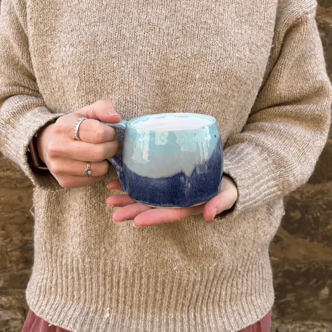 Landscape Large Round Mug, a person in a jumper holding a colourful coffee mug in front of them. 