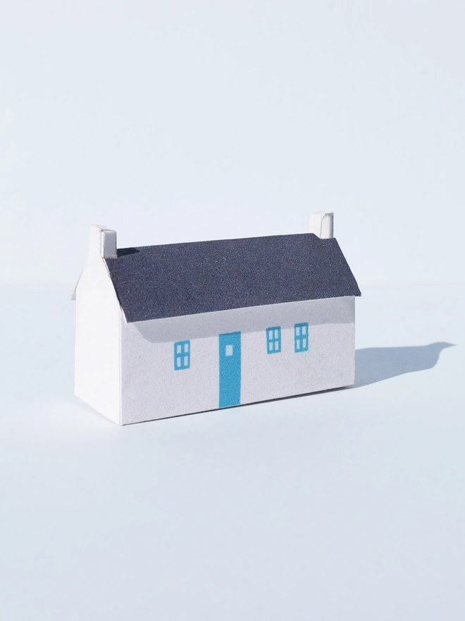 Paper house with white facade and blue doors and windows