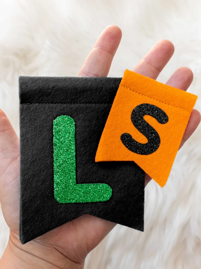 a hand holding 2 felt flags, showing the size difference between small and large.