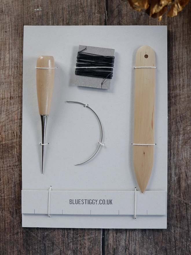 Bookbinding tools included in the kit - Awl, curved needle, linen thread, bamboo folder and measure