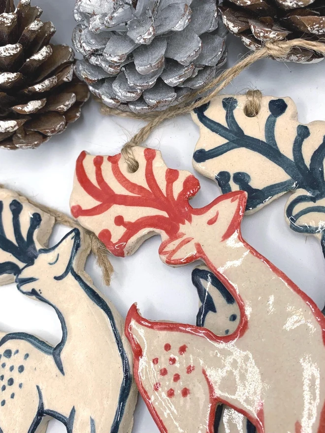 Handmade Ceramic Reindeer Ornament Scandinavian Folk Decor, a group of colourful reindeer decorations sitting on a plain white surface. 