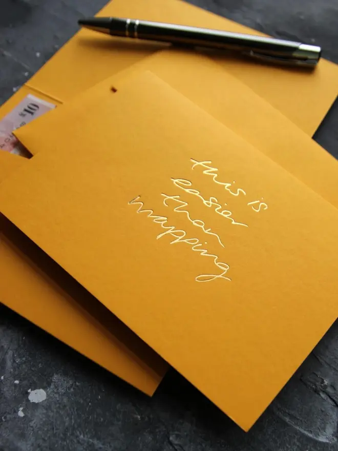 Hand foiled cash card or money wallet in a citrine colour in shiny gold foil text which says ‘this is easier than wrapping’.