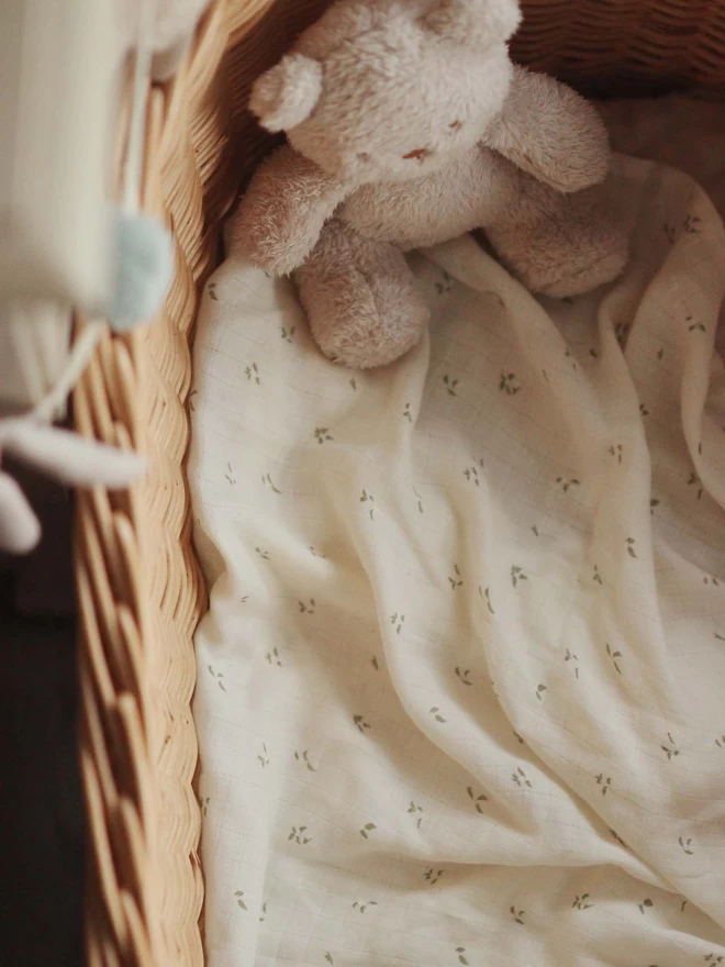 Nettle Scatter swaddle and a teddy bear in a changing basket