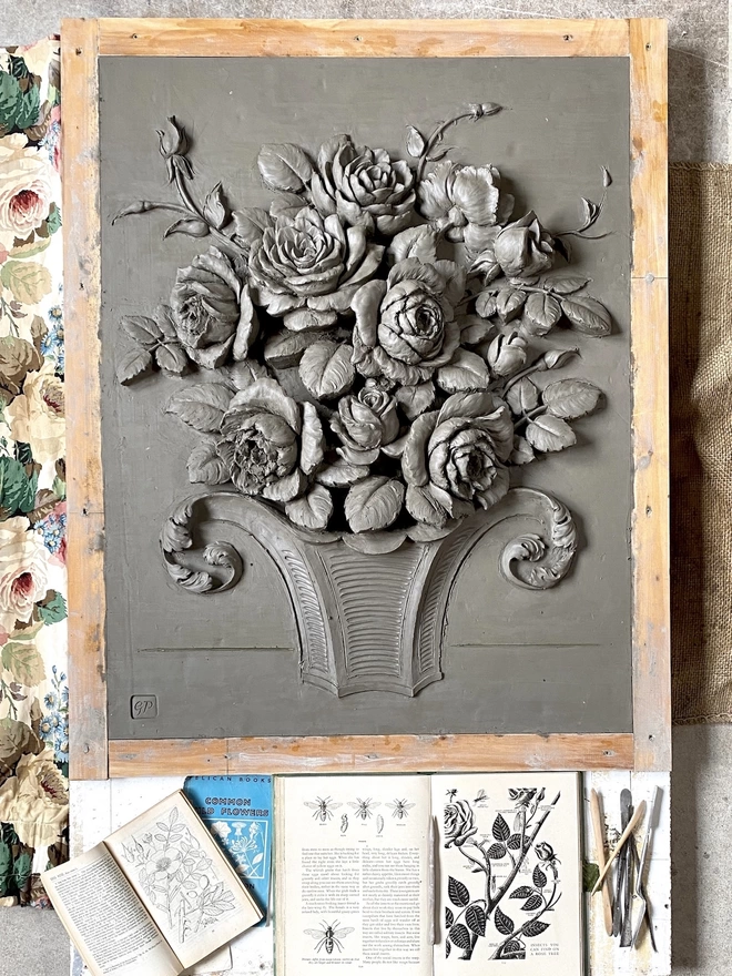 Clay model of a flower sculpture in a timber frame with inspiration images and chintz textile