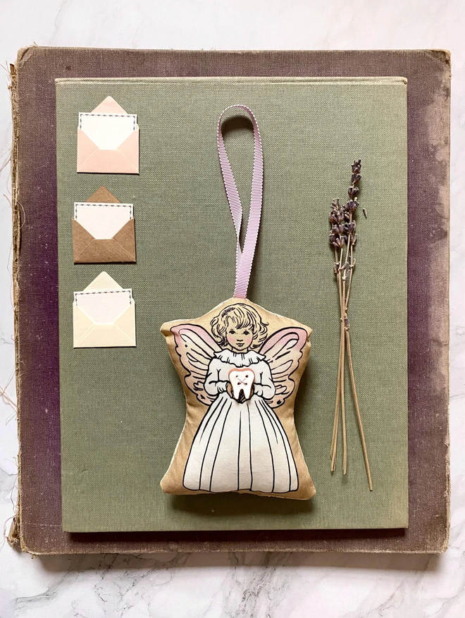 a tooth fairy decoration holding a ceramin tooth button