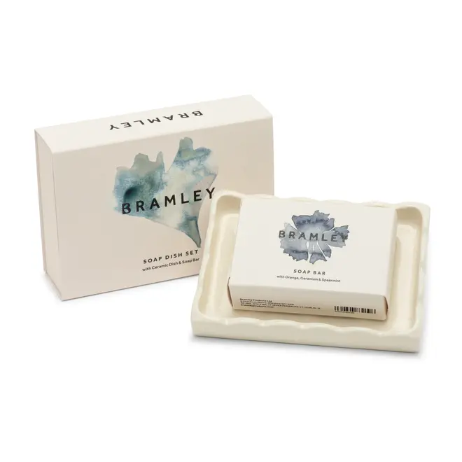 white cardboard box with blue logo that reads bramley, next to an off-white ceramic soap dish, with a smaller cardboard box with same logo sitting in it