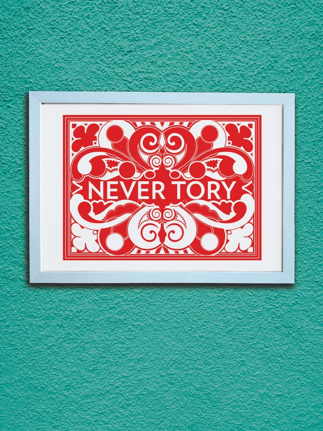 A bold, landscape red and white symmetrical illustration with Never Tory written in white at the centre. It is in a white frame hung on a textured teal wall.