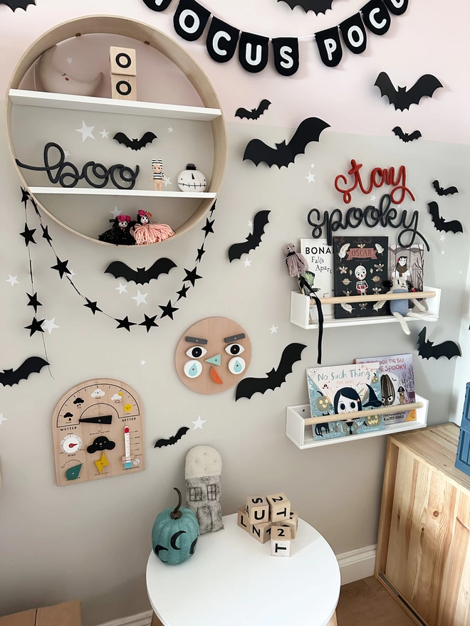 Lowercase 'boo' wall word decor on a round shelf in a child's stylish playroom full of small business decorations and fun wooden toys. 