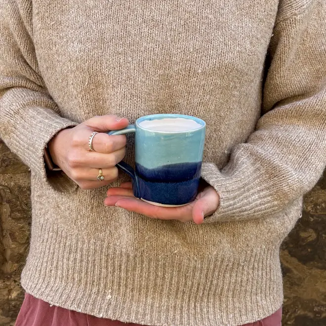 Landscape Standard Mug, a person wearing a jumper holding a colourful mug in front of them. 