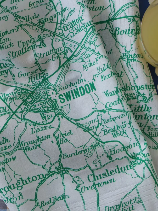 Detail of a Mr.PS Swindon map hankie printed in green, alongside a glass of orange juice