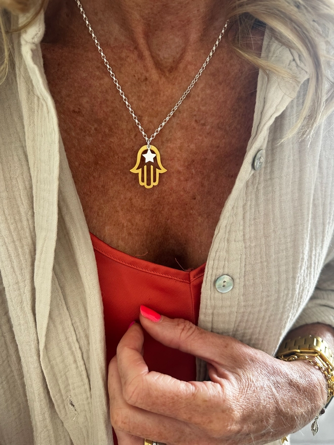model wears gold hamso hand charm on sterling silver chain with silver mini star
