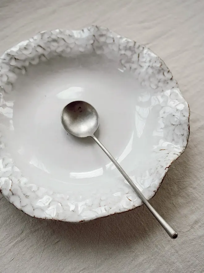 Dapple Stoneware Pasta Bowl, with a spoon placed on a table cloth. 