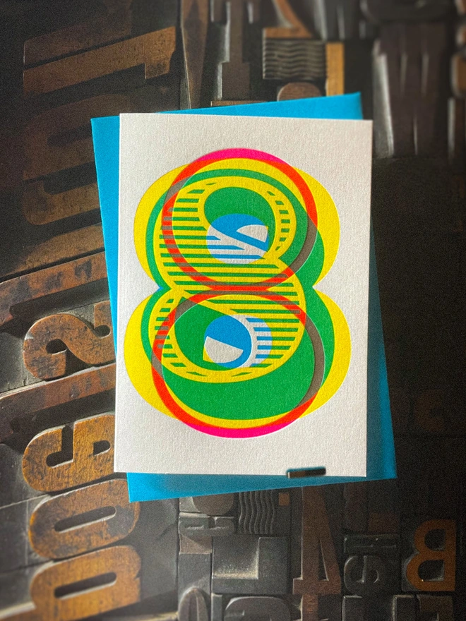 Handmade letterpress 8th birthday card featuring bold overlapping numerals printed in vibrant fluorescent cyan, magenta and yellow inks. Each card is individually hand printed using traditional letterpress techniques on luxury paper stock, creating a beautifully tactile finish with a deep impression and rich layered colours inspired by the CMYK printing process. Printed on a traditional letterpress from 1915. A wonderful artisan printed birthday card.