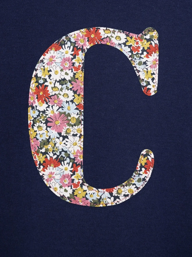  a personalised kids personalised navy t-shirt with an initial cut from Libby floral liberty print on the front, a close up of the stitching