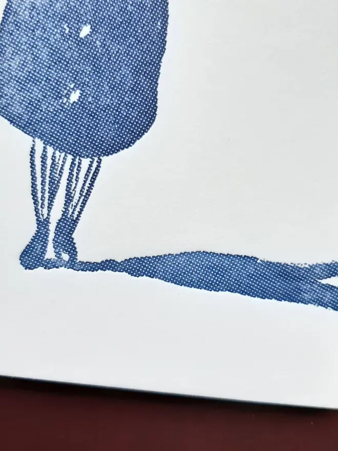 Blank Message Letterpress Handprinted Blue Greetings Card, a white card with a blue design sitting above a dark red background.