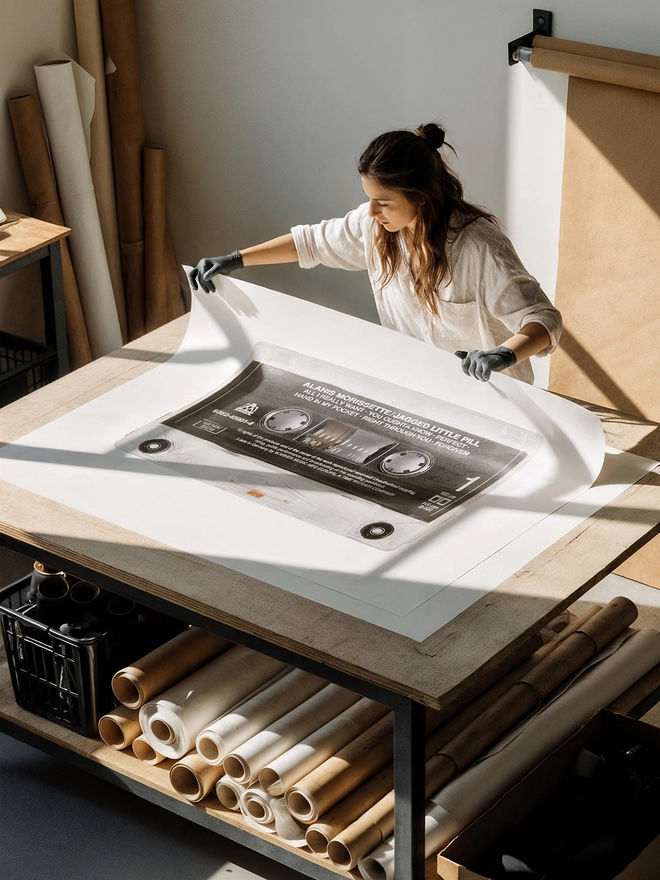 jagged little pill alanis morrisette cassette tape print. print being unrolled on table in artist studio.